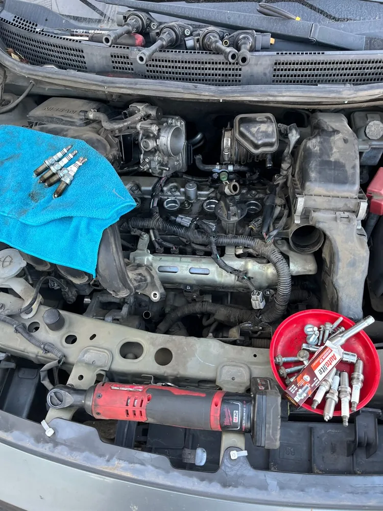 Ignition coils and spark plugs laid out over an open engine bay