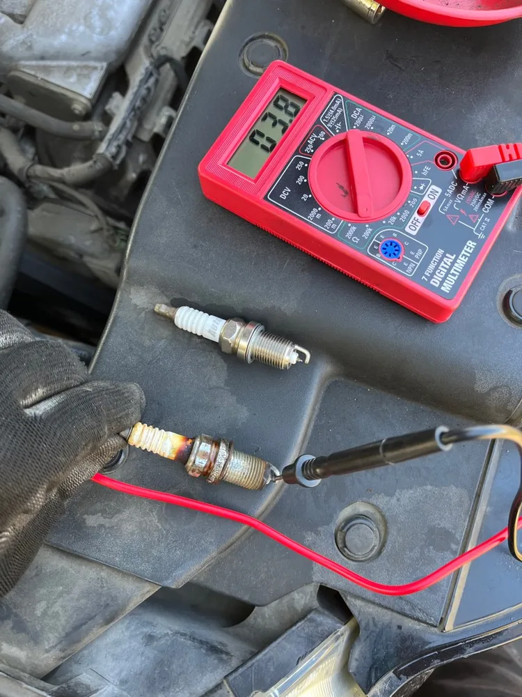 A multimeter testing a spark plug and coil