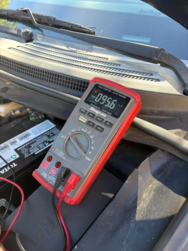 A multimeter on the cowl reading battery voltage