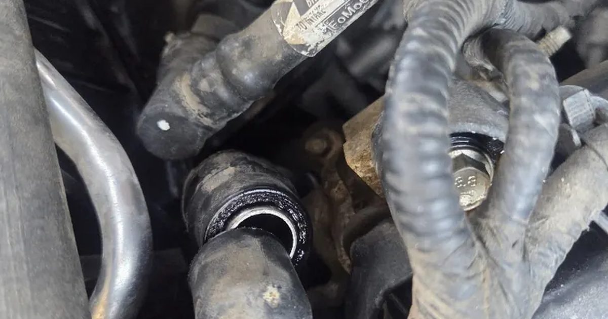Heater hoses and their fittings in the engine bay of a Ford during a cooling system job