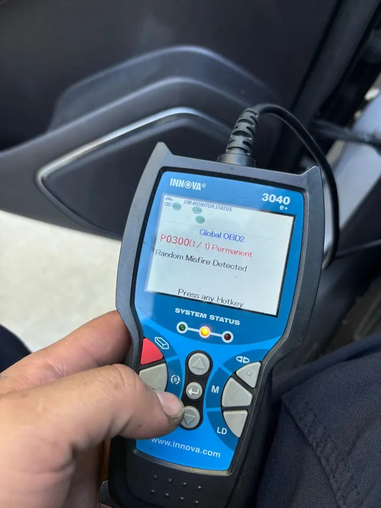 A handheld code reader showing a P0300 random misfire code