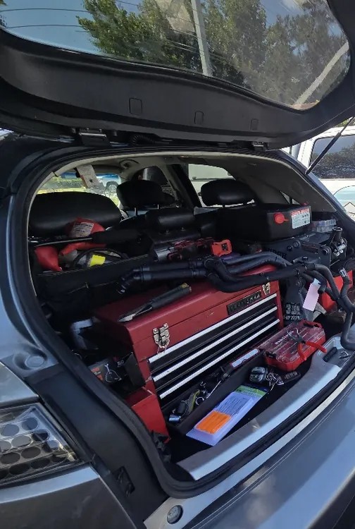 A red tool chest, hoses and power tools packed into the back of a service vehicle