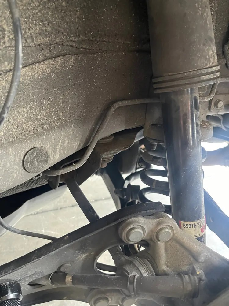 A rear shock absorber with its own coil spring mounted beside it under a car